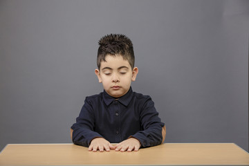 Small student boy sitting on wooden table