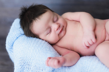 Smiling newborn baby boy. Newborn cute baby sleeping. Closeup portrait, caucasian child