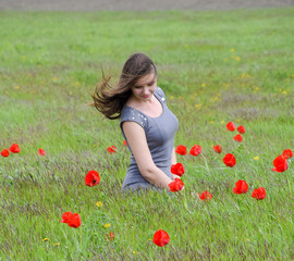 Beautiful fairy young girl in a field among the flowers of tulips. Portrait of a girl on a background of red flowers and a green field. Field of tulips