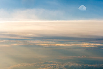 The colorful sky above the clouds with half moon airplane traveling in the summer