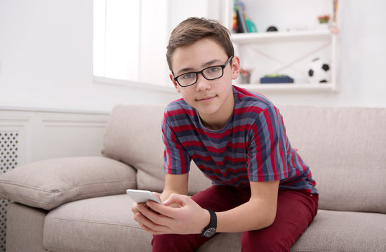 Teenager with mobile phone in living room at home