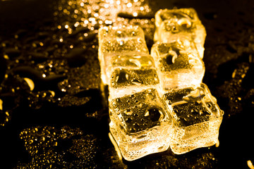 ice cubes and water drop on light golden background.