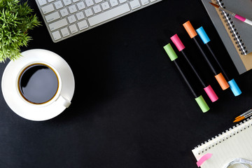 Office dark desk table with computer, office supplies and coffee cup with copy space.