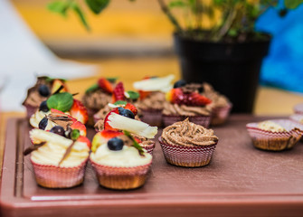 Different delicious cupcakes decorated with caramel and fresh berries.