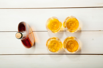 Glasses with cognac and a bottle on  white wooden background