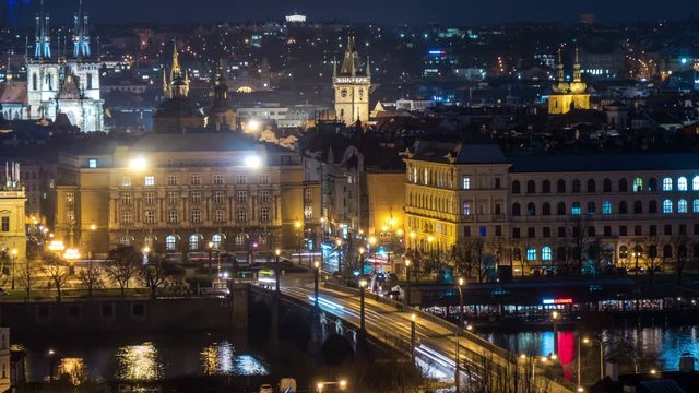 Wonderful view on the Charles bridge in Prague with old and arty sculptures, lit lanterns, streaming back and forth people in the evening twilights, in early spring, being taken as a timelapse shot