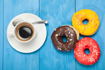 Cup with coffee and donuts on a blue wooden table