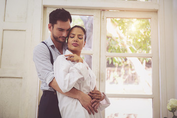 Couple standing by the window in the morning.