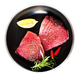 Raw tuna on a frying pan close up isolated on white background.