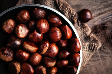 Raw Chestnuts  on old wooden table with copy space, close up. Beautiful chestnuts top view.