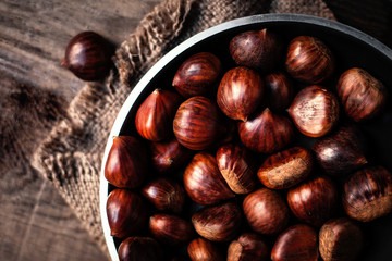 Heap  of edible fresh chestnuts on old wooden table. Group of ripe big chestnuts with copy space, macro