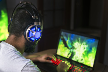 Young gamer playing video game wearing headphone. © sezer66