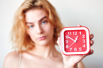 The concept of premature ejaculation men. Girl on a white background holding a red clock closeup - obrazy, fototapety, plakaty