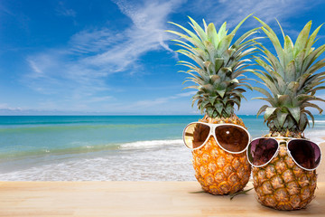 Naklejka premium pineapple with sunglasses on wood,concept summer background.