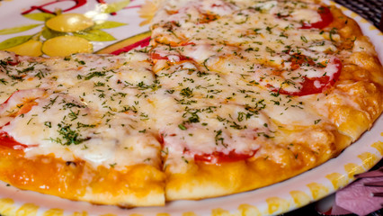 Pizza with tomatoes, mushrooms and cheese with greens, close-up