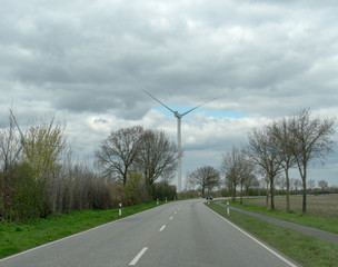 Windrad an der Strasse im Fr&uuml;hling mit B&auml;umen