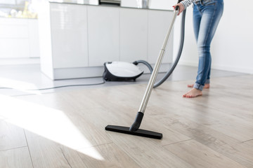 Fototapeta premium Woman using Vacuum Cleaner in Kitchen