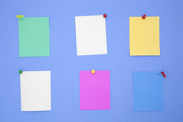 colorful paper note with pin on blue paper background.