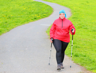 Overweight woman walking on meadows trail. Slimming and active lifestyle theme.