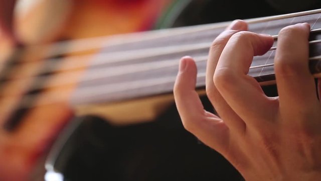 Close-up on Man hands playing on bass guitar.