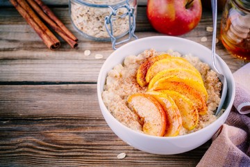 Healthy breakfast: oatmeal bowl with caramelized peaches, cinnamon and honey