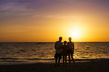 Fototapeta na wymiar Happy family standing on the beach at the sunset time. Parents. Concept of happy family.
