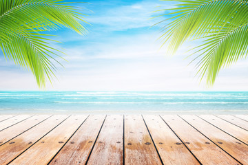 Empty wooden table and palm leafs with party on beach background blurred. Concept Summer, Beach, Sea, Relax, Party.