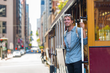 San Francisco man riding cable car tramway. Young casual guy in his 20s using public transport...