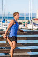 Athlete man stretching legs before running in San Francisco bay harbour - city lifestyle. Fitness...