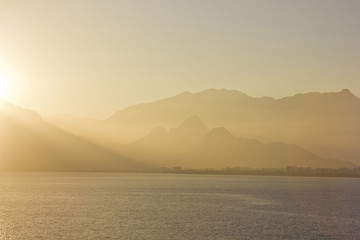 yellow sunset above sea with mountains on background