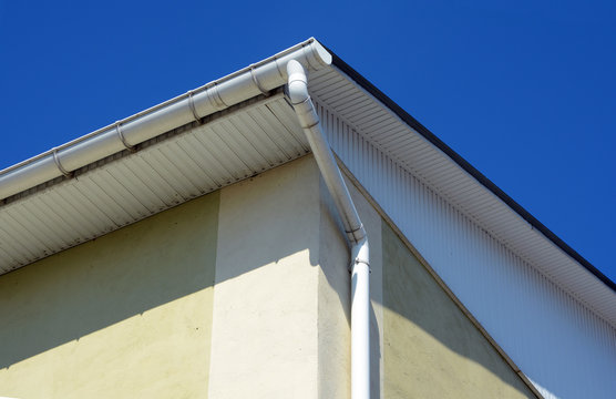 Rain gutters on a house. White gutter on the roof top of house. Guttering system