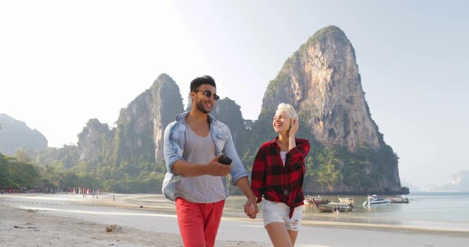 Couple Walking On Beach Holding Hands Talking Young Man And Woman Tourists On Vacation Slow Motion 60