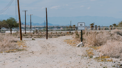 No trespassing sign, Salton Sea desert landscape view, wooden pole, California