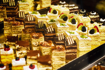 Fototapeta premium Different types of cakes in pastry shop glass display