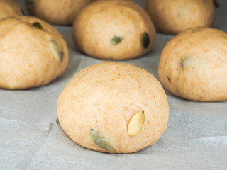 Pumpkin seed buns proofing on baking paper at close-up
