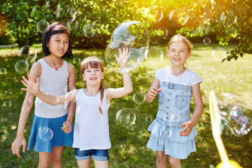 Kinder spielen im Sommer Seifenblasen fangen