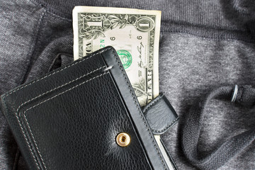 One dollar and a black purse against the gray trousers