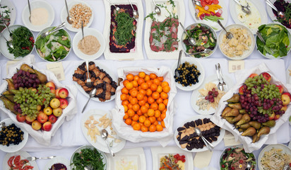 Top view of plates with delicious homemade food , garden berries, fruits, cups and Cutlery on the big table