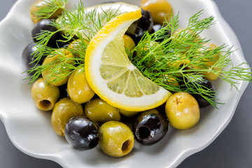 Sliced lemon with olives and dill close up on dark background