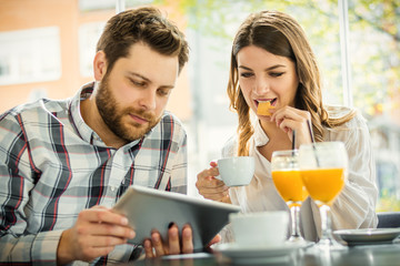 cheerful couple sitting in a cafe and using a digital tablet