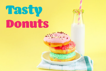 Plate with stack of delicious donuts and blurred bottle of milk on yellow background