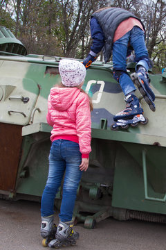 Two teen girls with rollers at war Bradley fighting vehicle