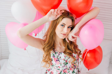 Girl in romantic dress with balloons in the shape of a heart