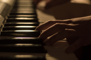 Close-up soft focused atmospheric photo of a hand playing the piano keys. Concept: Music creating,...