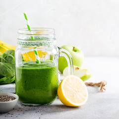 Healthy green smoothie with spinach, banana, lemon, apple and chia seeds in glass jar and ingredients. Detox, diet, healthy, vegetarian food concept with copy space.