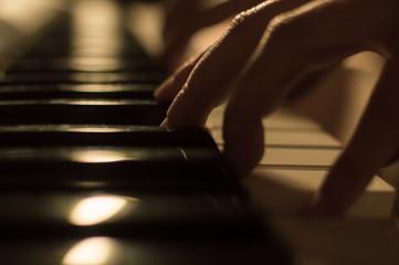 Close-up soft focused atmospheric photo of a hand playing the piano keys. Concept: Music creating,...
