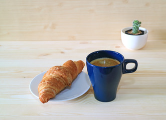 Coffee and Whole Wheat Croissant on the Wooden Table with a Mini Cactus Plants 