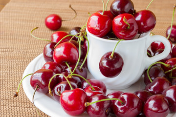 Cherries in a white cup on a wooden surface