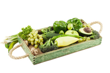 Set of different green fresh raw vegetables and fruits in the wooden tray