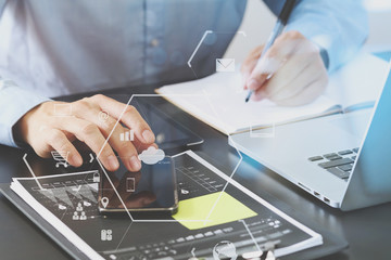 close up of businessman working with smart phone and digital tablet and laptop computer  on wooden desk in modern office with London city exposure